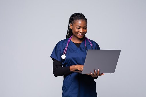 A GP in scrubs using a laptop for a telehealth consultation
