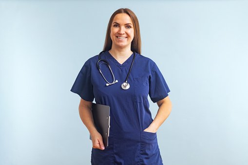 A clinician in navy scrubs reviewing notes on a clipboard