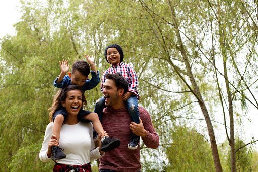 Parents giving two children a piggyback in a park